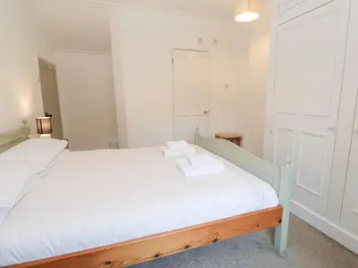 a bedroom with a white bed with two towels on it at Sunnyvale Cottage in Penzance