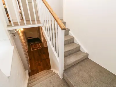 a staircase in a home with white walls and wooden floors at Sunnyvale Cottage in Penzance