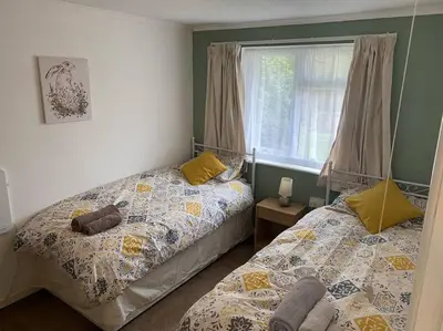 a bedroom with two beds next to a window at Light and bright 3 bedroom bungalow in Cornwall in Liskeard