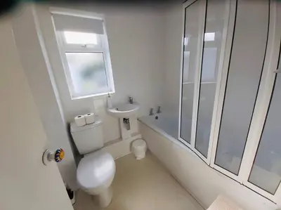 a white bathroom with a toilet and a sink at Light and bright 3 bedroom bungalow in Cornwall in Liskeard
