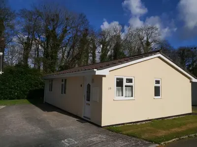 a small white building with a garage at Light and bright 3 bedroom bungalow in Cornwall in Liskeard