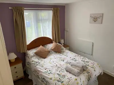 a bedroom with a bed with pillows and a window at Light and bright 3 bedroom bungalow in Cornwall in Liskeard