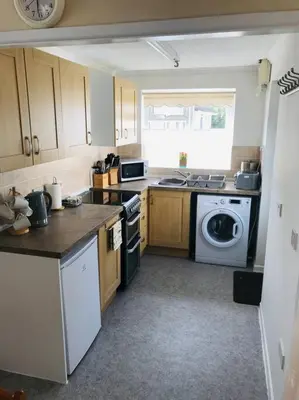 a kitchen with a stove and a washer and dryer at Light and bright 3 bedroom bungalow in Cornwall in Liskeard