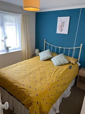 a bedroom with a bed with a yellow comforter at Light and bright 3 bedroom bungalow in Cornwall in Liskeard