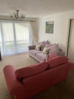 a living room with a red couch in front of a window at Light and bright 3 bedroom bungalow in Cornwall in Liskeard