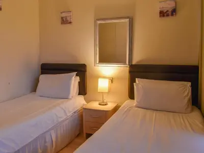 a bedroom with two beds and a lamp on a night stand at Atlantic Lodge in Saint Columb Major