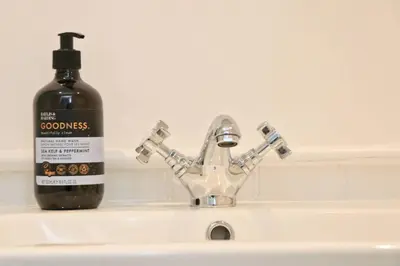a bottle of soap sitting on a bathroom sink with a soap dispenser at WALK TO THE BEACH, spacious cottage with sea views in St Merryn