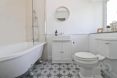 a bathroom with a toilet and a tub and a sink at WALK TO THE BEACH, spacious cottage with sea views in St Merryn