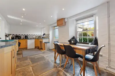 a large kitchen with a wooden table and chairs at Myrtle Cottage Boscastle in Boscastle
