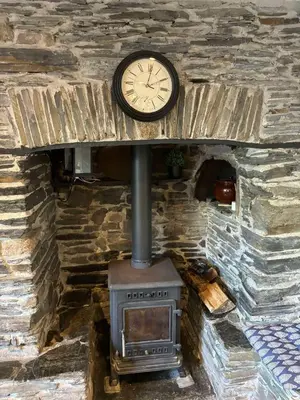 a clock on a brick wall with a stove at Myrtle Cottage Boscastle in Boscastle