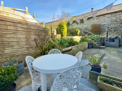 a white table and chairs in a garden at Myrtle Cottage Boscastle in Boscastle