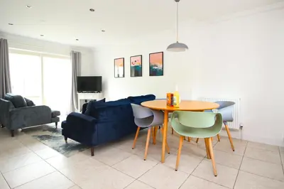 a living room with a table and a blue couch at BEACHSIDE modern home, dogs welcome in St Merryn
