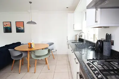 a kitchen with a wooden table and chairs in it at BEACHSIDE modern home, dogs welcome in St Merryn