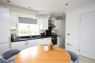a kitchen with a wooden table and blue chairs at BEACHSIDE modern home, dogs welcome in St Merryn