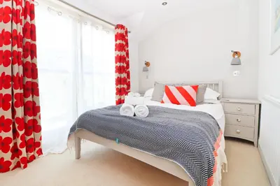 a bedroom with a bed with red and white curtains at BEACHSIDE modern home, dogs welcome in St Merryn
