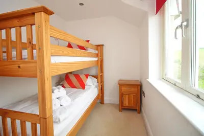 a bedroom with a bunk bed with a ladder at BEACHSIDE modern home, dogs welcome in St Merryn