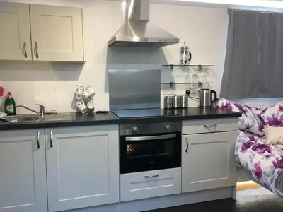 a kitchen with a stove top oven next to a couch at Tides Reach, Deluxe Shepherds hut 1, 100m from the Beach in St Merryn