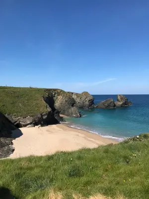 a sandy beach with rocks in the ocean at Tides Reach, Deluxe Shepherds hut 1, 100m from the Beach in St Merryn