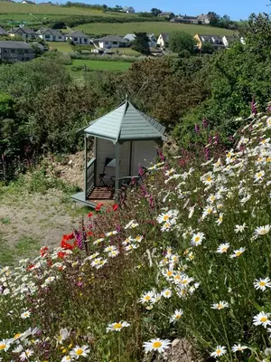 a gazebo in the middle of a field of flowers at Tides Reach, Deluxe Shepherds hut 1, 100m from the Beach in St Merryn