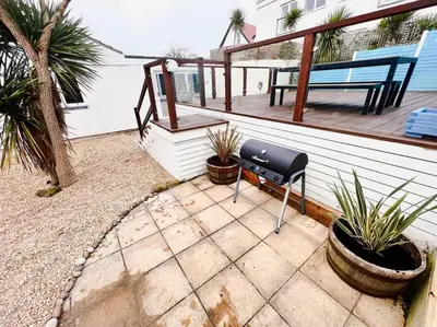 a patio with a bench and plants on a deck at The Hideout - Newquay - Fully Stocked Eco Escape in Newquay