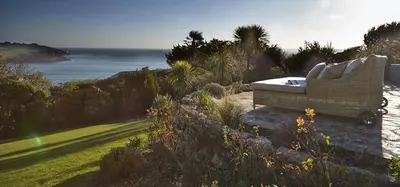 a bench sitting on top of a field with the ocean at Stargazers in Saint Mawes