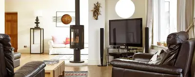 a living room with leather furniture and a flat screen tv at Stargazers in Saint Mawes