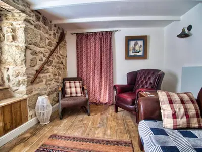 a living room with leather furniture and a stone wall at Knocker Cottage is a 3 bedroom made up of 1 double bedroom and 2 small double bedrooms in small village 10 min to beaches in Camborne