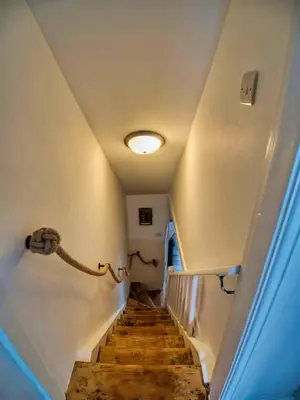 a hallway with a staircase with a light on the ceiling at Knocker Cottage is a 3 bedroom made up of 1 double bedroom and 2 small double bedrooms in small village 10 min to beaches in Camborne