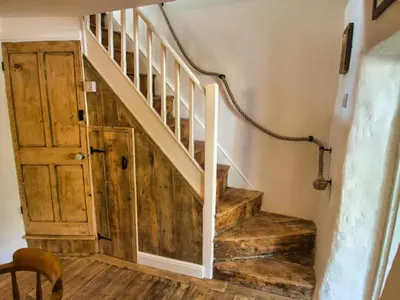 a staircase in a house with a wooden door at Knocker Cottage is a 3 bedroom made up of 1 double bedroom and 2 small double bedrooms in small village 10 min to beaches in Camborne