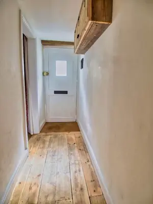 a hallway with a white door and a wooden floor at Knocker Cottage is a 3 bedroom made up of 1 double bedroom and 2 small double bedrooms in small village 10 min to beaches in Camborne