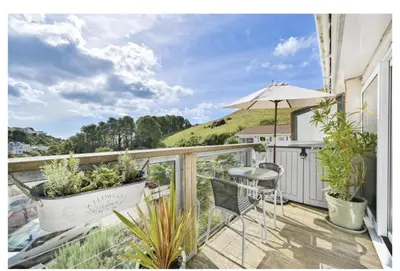 a balcony with a table and chairs and an umbrella at Torpoint - Apartment - Sleeps4 - Seaside - Parking in Torpoint