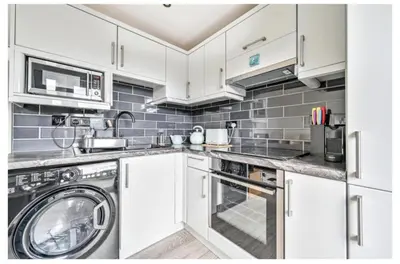 a kitchen with white cabinets and a washer and dryer at Torpoint - Apartment - Sleeps4 - Seaside - Parking in Torpoint