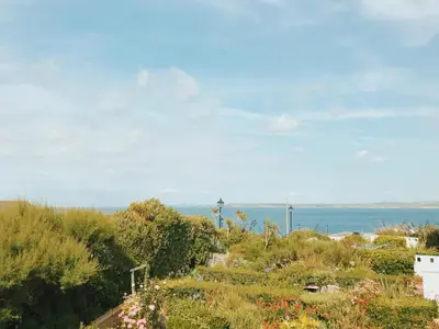 a view of a garden with the ocean in the background at Sands Studio and Samphire Studio in St Ives