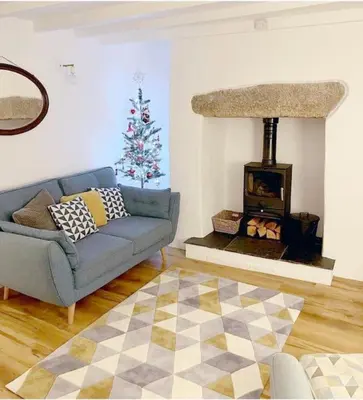 a living room with a blue couch and a christmas tree at Beach Lovers Paradise in Portreath - With Sea Views & Log Burner just 100m from beach in Portreath