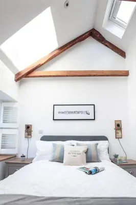 a bedroom with a white bed with two windows at Beach Lovers Paradise in Portreath - With Sea Views & Log Burner just 100m from beach in Portreath