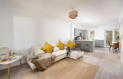 a living room with a white couch and yellow pillows at Towans Retreat, Hayle in Hayle