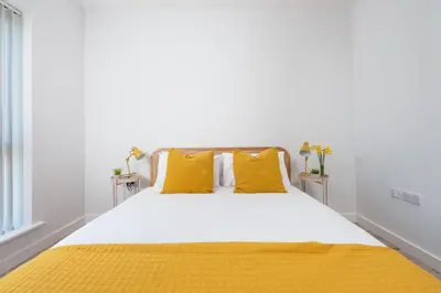 a white bedroom with yellow pillows and a bed at Towans Retreat, Hayle in Hayle