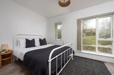 a white bedroom with a bed and two windows at Towans Retreat, Hayle in Hayle