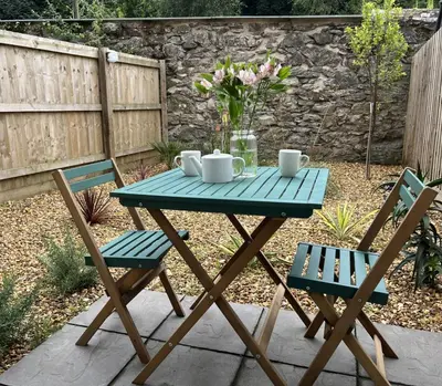 a picnic table with two chairs and a table with mugs at Towans Retreat, Hayle in Hayle