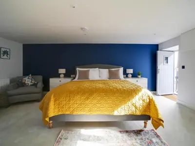 a bedroom with a bed and a blue wall at Joinery Cottage in Porthleven