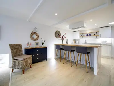 a kitchen with a counter and a bar with stools at Joinery Cottage in Porthleven