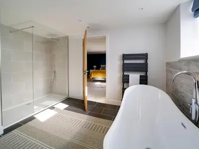 a bathroom with a bath tub and a shower at Joinery Cottage in Porthleven