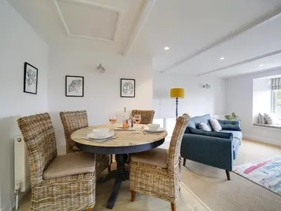 a dining room with a table and chairs and a couch at Joinery Cottage in Porthleven