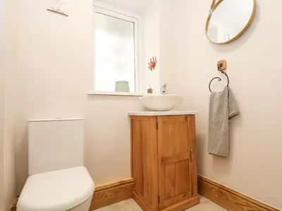a bathroom with a sink and a toilet and a mirror at Woodbine Cottage in Falmouth