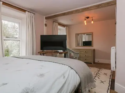 a bedroom with a bed and a flat screen tv at Woodbine Cottage in Falmouth