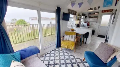 a kitchen and dining room with a table and a view of a balcony at F17 Up-A-Bank, Riviere Towans in Hayle