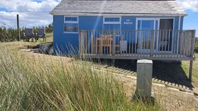 a blue house with a deck in a field at F17 Up-A-Bank, Riviere Towans in Hayle