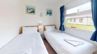 two beds in a room with a window at F15 Brian View, Riviere Towans in Hayle