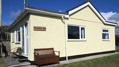 a yellow house with a bench in front of it at F15 Brian View, Riviere Towans in Hayle