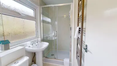 a white bathroom with a sink and a shower at F15 Brian View, Riviere Towans in Hayle